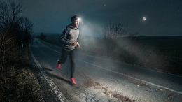 Person running on a dark road with a flashlight at night