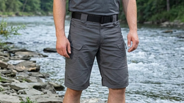 Person wearing gray shorts standing by a river